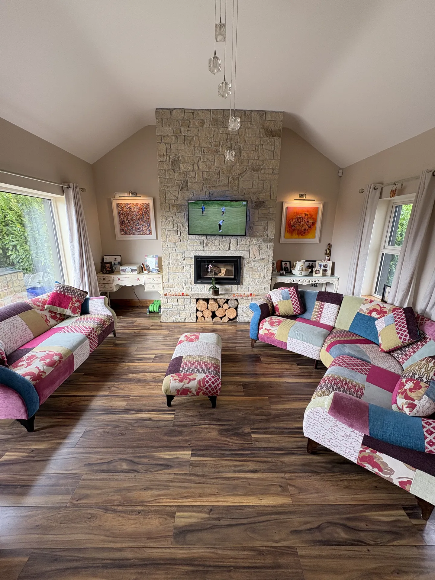 Formal sitting room with vaulted ceiling, stone fireplace and original art